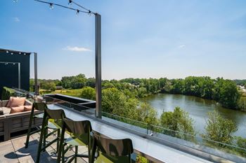 A balcony with a table and chairs overlooking a river.